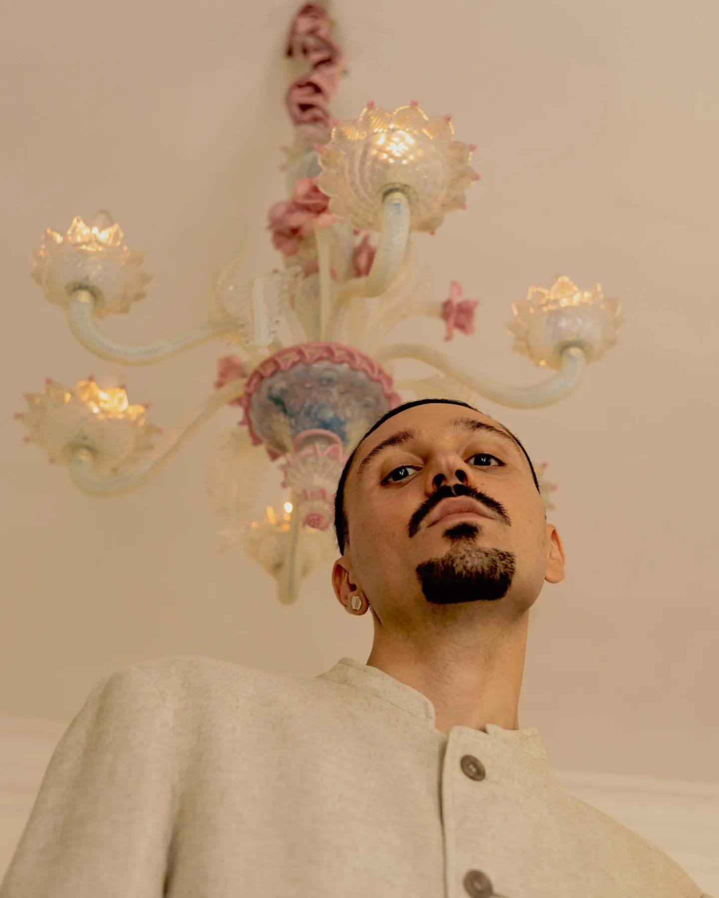 Model in a cream wool jacket beneath an ornate glass chandelier